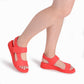 modelando sandalias color coral de cuña media hechas de elastano y ajuste con velcro para mujer