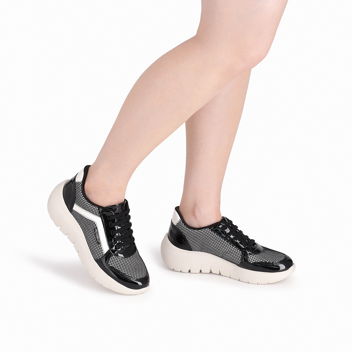 Modelo con un par de tenis color blanco y negro casuales para mujer, colección Eliane, cuña media 3.5 cm. Estilo casual y cómodo con amortiguación, suela flexible y diseño versátil.